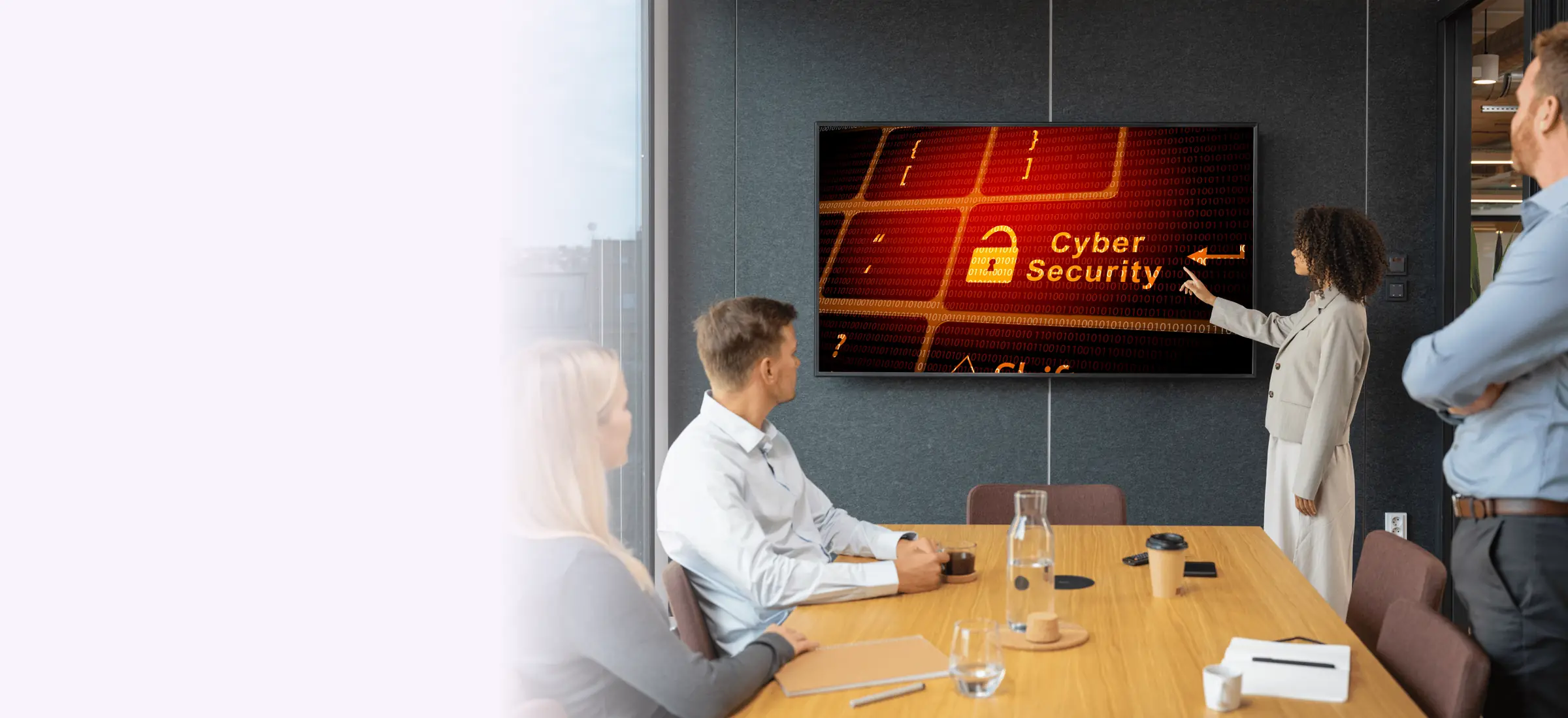 A business team in a meeting room reviewing a cyber security briefing on a wall screen