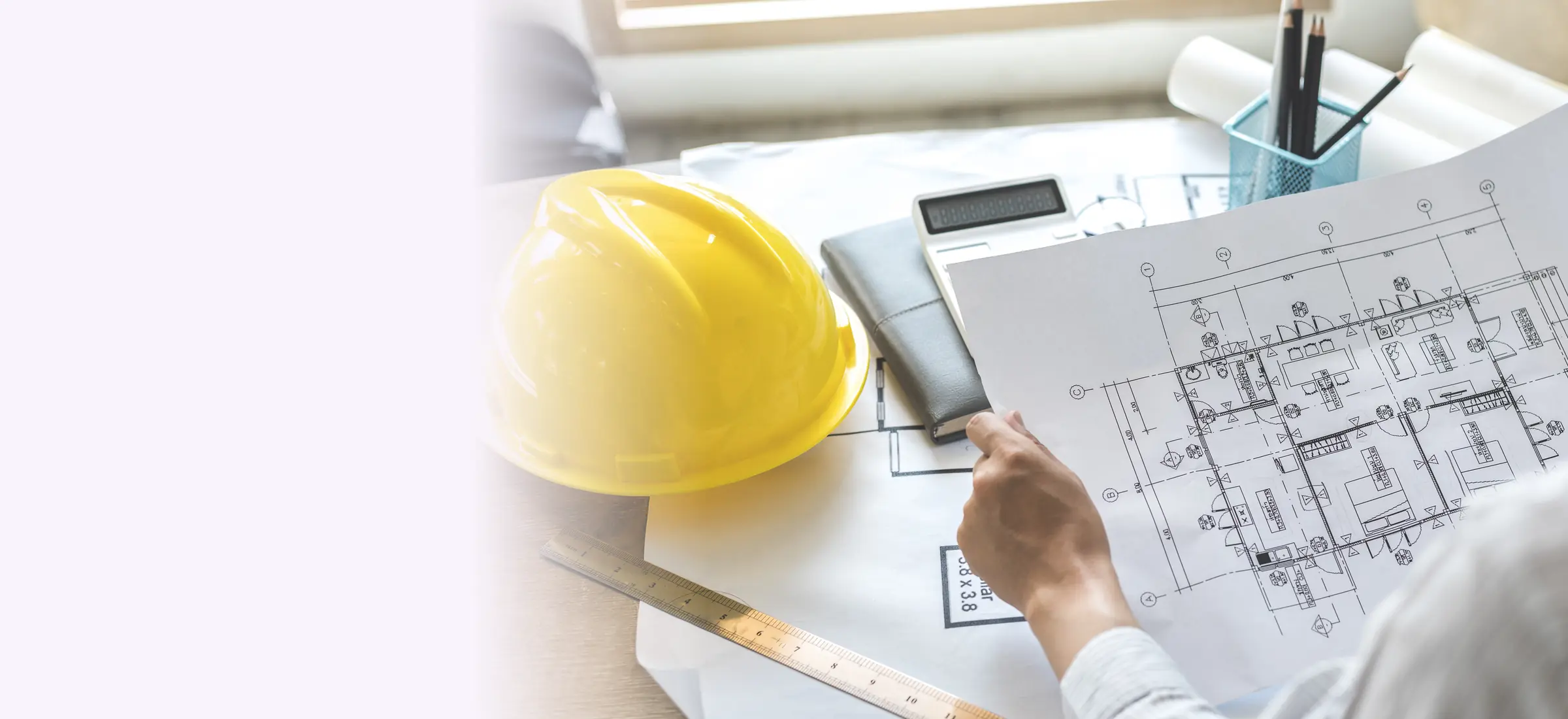 An architect reviewing building drawings beside a hard hat